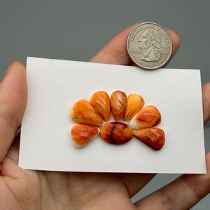 May include: A set of three ceramic mugs with a speckled, matte finish. The mugs are in shades of cream, light gray, and dark gray. Each mug has a simple, minimalist design and a rounded handle.