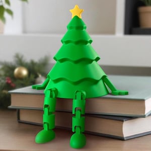 May include: A green Christmas tree bookend with articulated legs and a yellow star. The bookend sits on two books. The tree is a bright green colour. The books are on a wooden surface.
