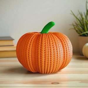 May include: An orange pumpkin with a textured, woven design. The pumpkin has a green stem and sits on a wooden surface. The pumpkin is a decorative item.
