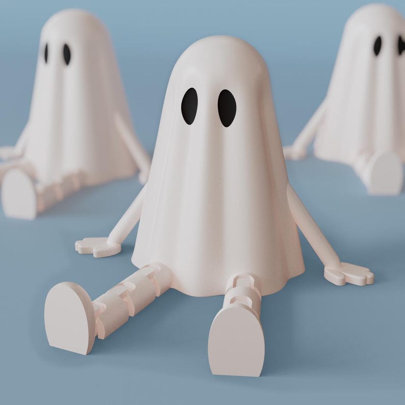Op de afbeelding: Drie witte spookfiguren met zwarte ovale ogen en beweegbare armen en benen zijn geplaatst op een lichtblauwe ondergrond. De geesten zitten in een zittende positie, met hun benen uitgestrekt. Het thema is Halloween.