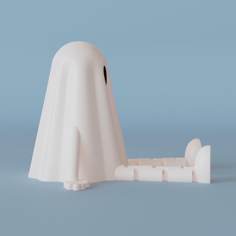Op de afbeelding: Een wit spookvormig object met een enkel zwart oog, zittend met uitgestrekte benen. De geest heeft een gedrapeerde vorm en een gestileerde voet. De achtergrond is effen lichtblauw.