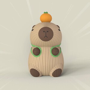 May include: A brown knitted capybara with green yarn accents and a small orange pumpkin on its head.