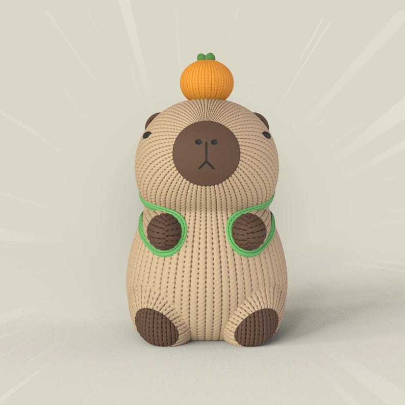 May include: A brown knitted capybara with green yarn accents and a small orange pumpkin on its head.