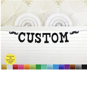 May include: A black glitter "CUSTOM" banner with mustache accents, strung on a black string. The banner is displayed against a white background with decorative paper fans. The image also shows a color palette of 15 glitter colors.