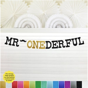 May include: A black and gold glitter banner that reads "MR ONEDERFUL". The banner is pre-strung and custom made to order.