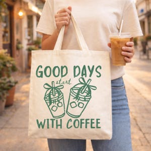 K&ouml;nnte beinhalten: Cremefarbene Tragetasche mit gr&uuml;nem Text "GOOD DAYS start WITH COFFEE" und Illustrationen von zwei Kaffeetassen. Die Tasche wird von einer Person getragen, die ein wei&szlig;es T-Shirt und blaue Jeans tr&auml;gt.