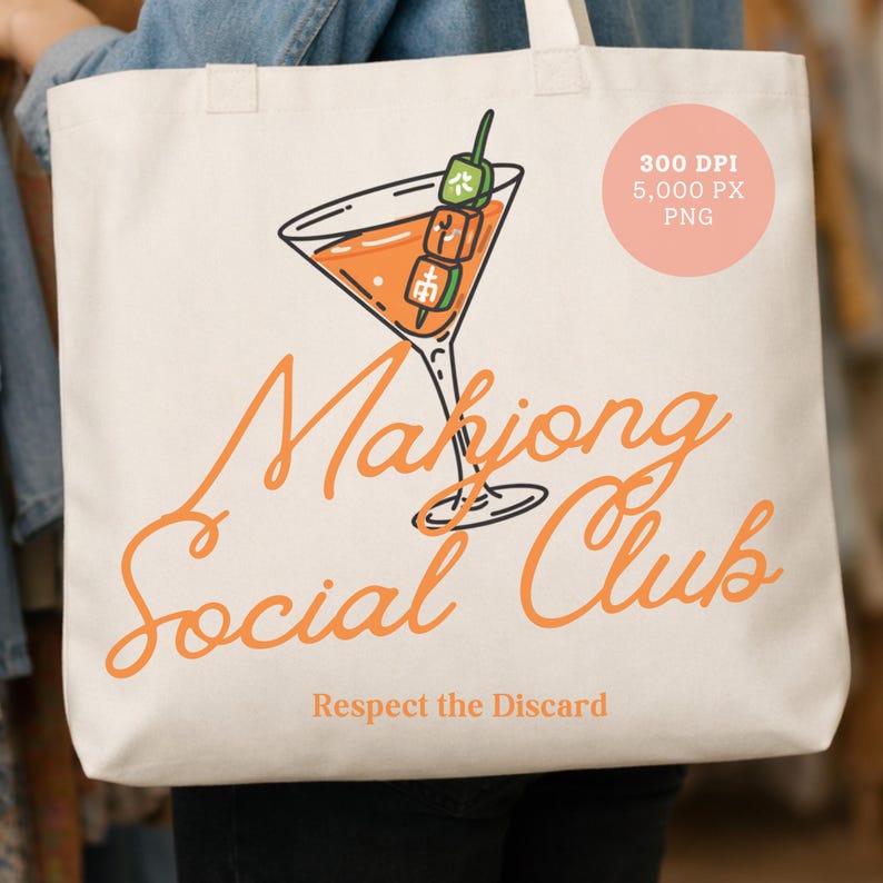 K&ouml;nnte beinhalten: Cremefarbene Tragetasche mit einer orangefarbenen Cocktail-Illustration und einer gr&uuml;nen und orangefarbenen Garnitur. Die Worte "Mahjong Social Club" sind in orangefarbener Schrift geschrieben, darunter "Respect the Discard". Ein rosa Kreis mit Text befindet sich oben rechts.