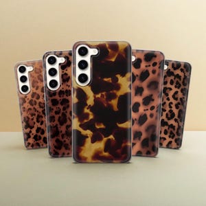 May include: Five different phone cases with various animal print designs. The cases are all clear and show the phone's camera lens. The designs include a tortoiseshell pattern, a leopard print, and a cheetah print.
