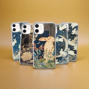 May include: Five clear phone cases with different designs. The cases feature a white rabbit, flowers, and a crescent moon. The cases are all for the iPhone 13 Pro.