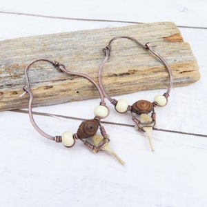 May include: Copper hoop earrings with white and brown beads and a small bone charm hanging from each hoop.