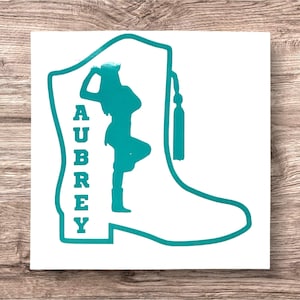 May include: Teal blue silhouette of a dancer in a boot with the name Aubrey written vertically on the side of the boot.