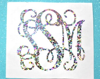 May include: A silver glitter monogram with the letters "SM" in a cursive script font.