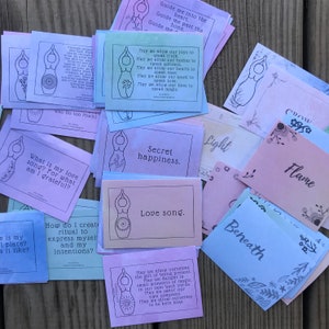 May include: A set of colorful cards with illustrations of a female figure and inspirational text. The cards feature phrases like "Secret happiness", "Love song", and "May we allow our joys to speak truth".