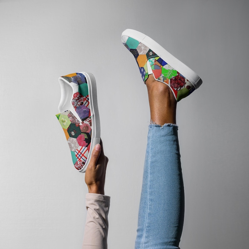 May include: A pair of white slip-on canvas shoes with a colorful patchwork design. The shoes are made of different fabrics and patterns, including floral, geometric, and plaid.