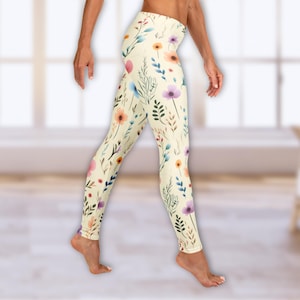 May include: A pair of yellow leggings with a floral print featuring pink, blue, and purple flowers. The leggings are made of a soft, stretchy material and are perfect for yoga, running, or everyday wear.