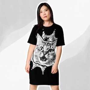 May include: Black t-shirt dress with a white graphic of a cat's face in a pixelated style.