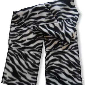 May include: A black and white zebra print fleece scarf. The scarf is folded in half and has a seam down the center.