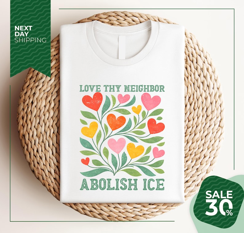 A white t-shirt with a colorful graphic design featuring a tree with heart-shaped leaves and flowers, along with the text "LOVE thy neighbor ABOLISH ICE". The t-shirt is displayed on a woven basket, and there is a green banner with text that reads "NEXT DAY SHIPPING" and "SALE 30%".