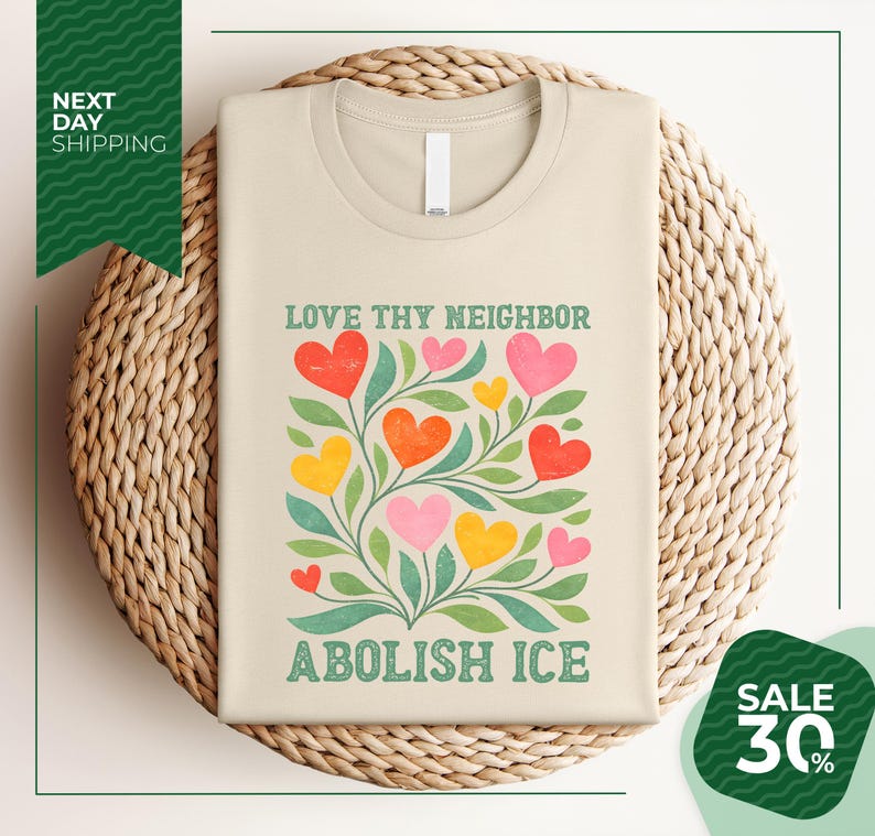 a beige t-shirt with a colorful graphic design of hearts and leaves, along with the text "Love thy neighbor" and "Abolish ice" printed on it. The t-shirt is displayed on a woven basket, and there is a green banner with white text that reads "Next day shipping" and "SALE 30%".
