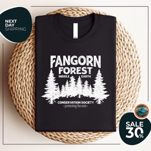 a black t - shirt with a forest scene on it