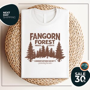 a white t - shirt with a forest scene on it