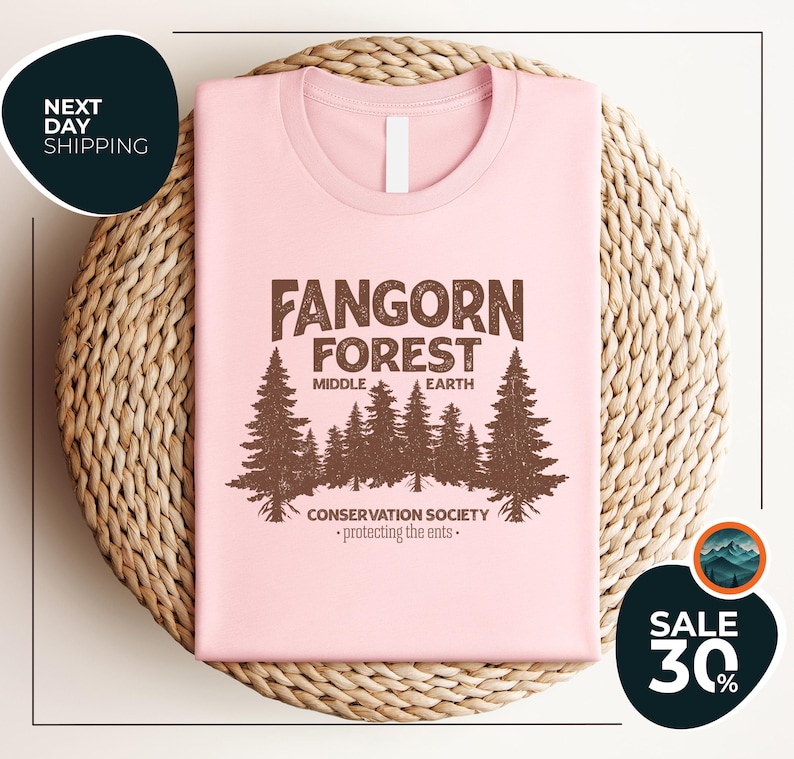 a pink t - shirt with a forest scene on it