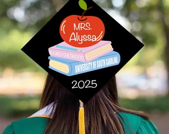 May include: A black graduation cap with a red apple design, the name "Mrs. Alyssa", and the year 2025. The apple sits atop two books, one pink and one blue, with the words "Early Childhood" and "University of South Carolina". A gold tassel hangs from the cap.
