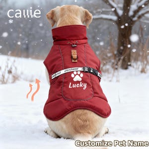 May include: A burgundy dog jacket featuring the word "Lucky" and a paw print. The jacket has a high collar, buckle closure, and a strap with "DUOMM". The dog sits in snow. The word "Callie" is at the top. The text "Customize Pet Name" is at the bottom.