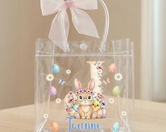 Bolsa de regalo transparente personalizada con lazo rosa, huevos de Pascua coloridos, pollitos y conejos, con nombre e inicial, ideal como recuerdo de fiesta de Pascua para niños.