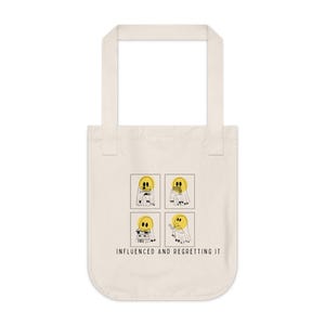 Puede incluir: Bolso tote de color crema con un diseño rectangular. Cuatro paneles muestran una figura amarilla con forma de fantasma con un contorno negro, en diferentes poses. El texto "INFLUENCED AND REGRETTING IT" está impreso debajo.