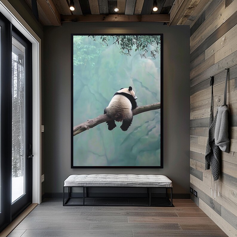 May include: A black and white panda bear sitting on a branch with a blurred green and blue background. The panda is facing away from the camera and has its head resting on the branch.