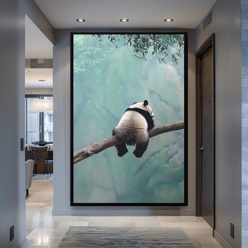 May include: A black and white panda bear sits on a branch in a green and blue forest. The panda is looking to the right of the image.