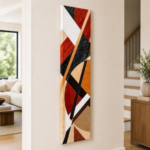 May include: A tall, narrow rectangular wall art piece featuring a geometric composition of intersecting lines and shapes. The design incorporates a palette of deep red, black, white, tan, and brown, with a visible textured finish across the surface.