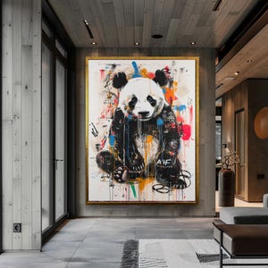 May include: A colourful abstract painting of a panda bear with black and white fur. The panda is sitting down with its paws in front of it. The background is a white canvas with splashes of colour, including red, blue, green, yellow, and orange.