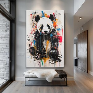 May include: A colourful abstract painting of a panda bear sitting on a white background. The panda is wearing a black and white jacket with graffiti-style lettering. The background is filled with splashes of colour, including red, blue, yellow, and green.