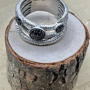 May include: A silver ring with three black gemstone accents. The ring is marked with the number "9925" and the letter "BH".