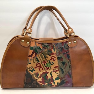 Könnte beinhalten: Eine braune Lederhandtasche mit zwei Griffen und einem dekorativen Patchwork-Panel. Der Patchwork-Bereich weist eine Vielzahl von Farben auf, darunter Rot, Grün und Gelb. Die Tasche hat goldfarbene Beschläge und einen Schnallenverschluss.