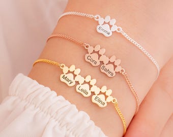 May include: Four gold paw print charm bracelets with the names "Mary", "Leila", "Elina", "Cora", "Sahra", and "Emma" engraved on them.