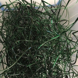May include: A close-up image of a container filled with tangled green and black plastic tubing.
