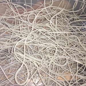 May include: A close-up image of a pile of tangled, silver-colored wire hangers.