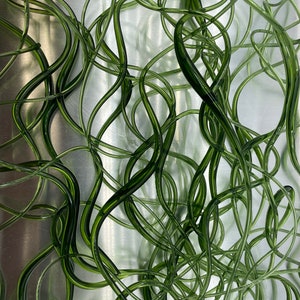 May include: Abstract image featuring a dense arrangement of intertwined, translucent green tubes. The tubes have a glossy finish and varying shades of green, creating a sense of depth. The background is a brushed metal surface, providing a contrasting texture.