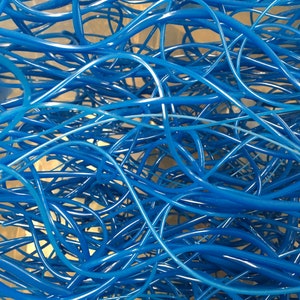 May include: A close-up of a tangled mass of blue plastic tubing. The tubing is arranged in a random pattern, creating a chaotic and abstract image.