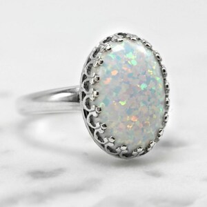 May include: A silver ring with a white opal gemstone set in a delicate filigree design.