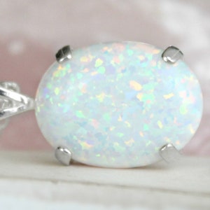 May include: A white opal pendant with a silver setting. The opal has a milky white color with iridescent flashes of color.