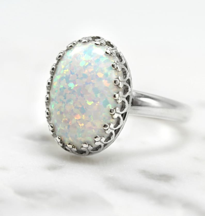 May include: A silver ring with a white opal gemstone set in a delicate filigree design.