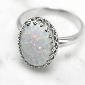 May include: A silver ring with a white opal gemstone set in a delicate filigree design.