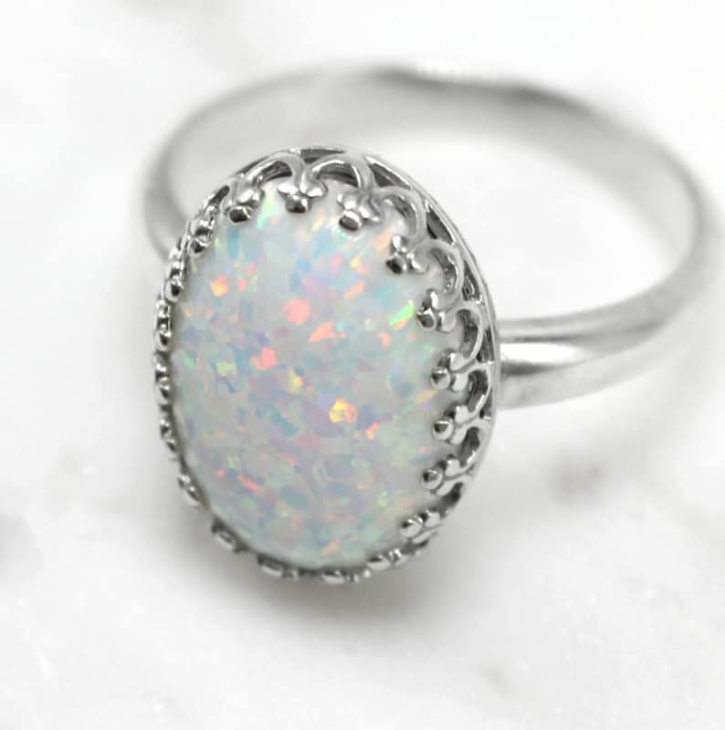 May include: A silver ring with a white opal gemstone set in a delicate filigree design.