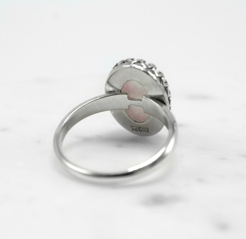 May include: A silver ring with a pink opal stone set in a decorative silver bezel. The ring is marked "12625" on the inside of the band.