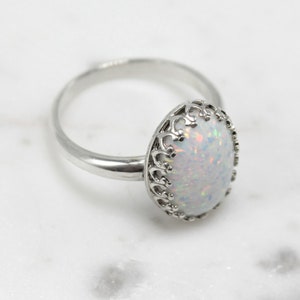 May include: A silver ring with a white opal stone set in a delicate filigree design.