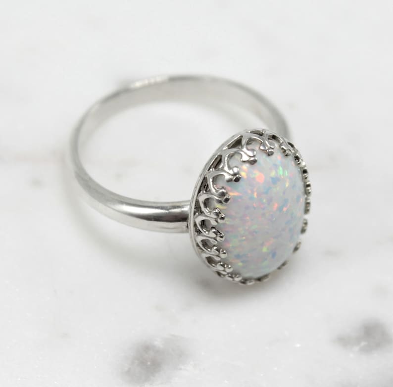 May include: A silver ring with a white opal stone set in a delicate filigree design.